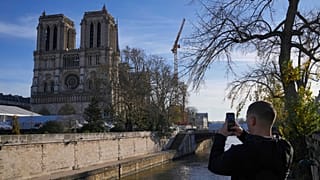 Un homme prend une photo de la cathédrale Notre-Dame alors que le président français Emmanuel Macron visite la cathédrale rénovée, le vendredi 29 novembre 2024 à Paris.