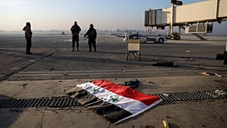 Eine syrische Flagge liegt auf dem Boden, während Oppositionskämpfer am Montag, dem 2. Dezember 2024, auf der Rollbahn des internationalen Flughafens von Aleppo stehen.