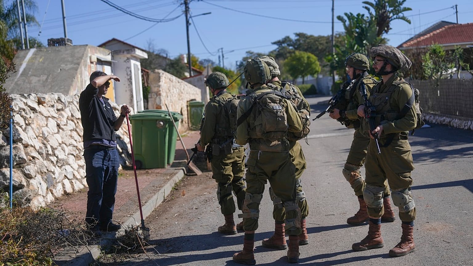 İsrail Savunma Kuvvetleri'ne (IDF) bağlı askerler Lübnan sınırında yer alan bir köyde, bir bölge sakiniyle konuşuyor, 2 Aralık 2024