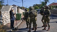 İsrail Savunma Kuvvetleri'ne (IDF) bağlı askerler Lübnan sınırında yer alan bir köyde, bir bölge sakiniyle konuşuyor, 2 Aralık 2024