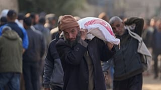 رجل يحمل كيسًا من الدقيق في مركز تابع للأونروا في مخيم النصيرات للاجئين، قطاع غزة، الثلاثاء 3 ديسمبر، 2024.
