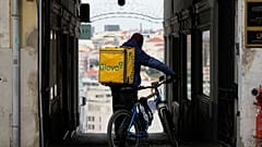 Un repartidor de guantes se detiene en un callejón de Lisboa, el lunes 27 de febrero de 2023. (Foto AP/Armando Franca)