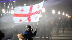 Un manifestant tient un drapeau national géorgien alors qu'il est aspergé par un canon à eau devant le parlement lors d'une manifestation, à Tbilissi, Géorgie, mardi 3 décembre 2024.