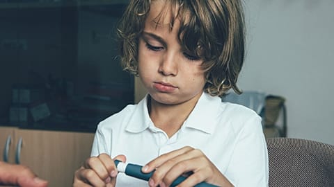 A child uses an insulin pen at the doctor's office.