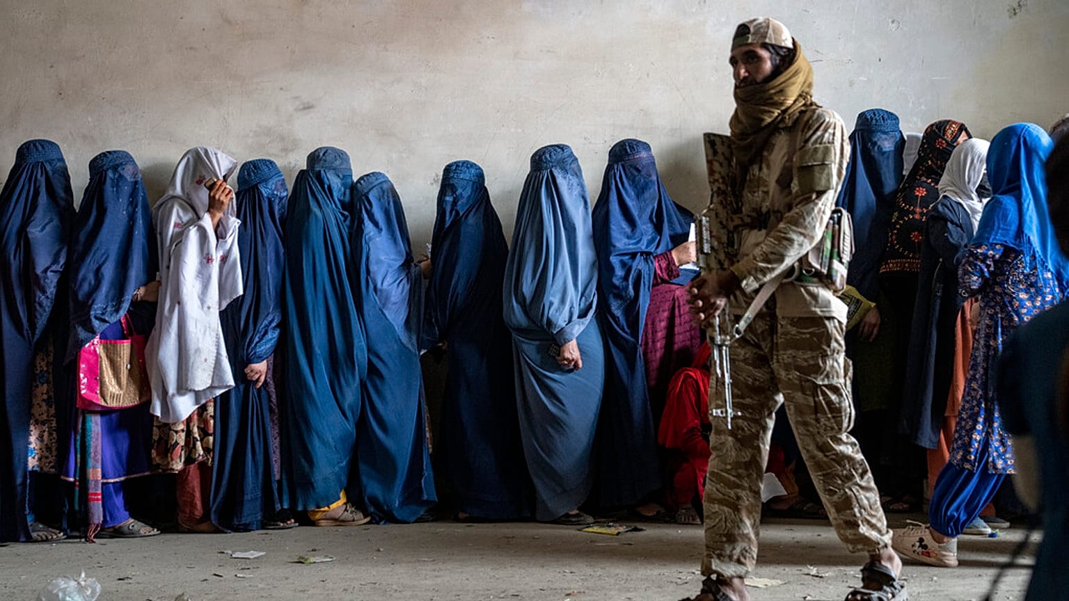 Bir Taliban savaşçısı, Afganistan'ın başkenti Kabil'de bir insani yardım için bekleyen kadınların başında nöbet tutuyor,  23 Mayıs 2023