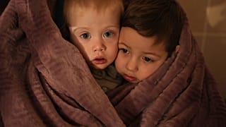Les enfants des travailleurs médicaux se réchauffent avec une couverture alors qu'ils attendent leurs parents dans un hôpital de Marioupol, en Ukraine, le vendredi 4 mars 2022