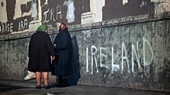 DOSYA: 1972'de Kuzey İrlanda'nın Belfast kentinde bir duvara yazılmış siyasi sloganlar fonunda kadınlar kaldırımda sohbet ediyor. 