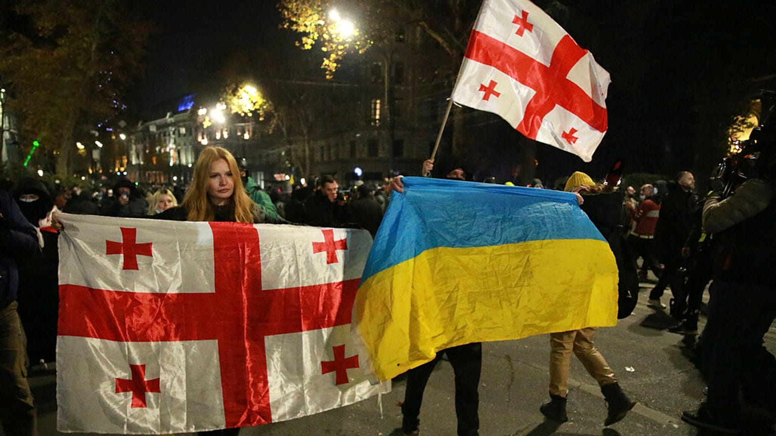 Des manifestants brandissent les drapeaux nationaux géorgien et ukrainien lors d'une manifestation anti-gouvernementale à Tbilissi, en Géorgie, le mardi 3 décembre 2024. 