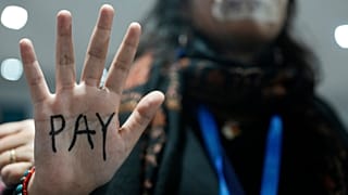 An activist displays "pay" on their hand as they participate in a demonstration for climate finance at COP29.