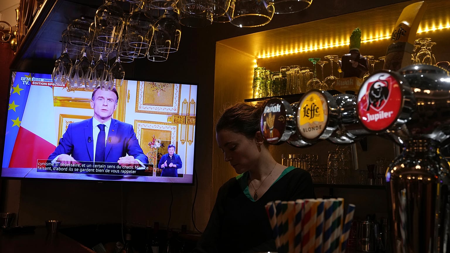 President Emmanuel Macron's speech plays on a television in a bar in Versailles, 5 December, 2024
