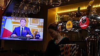 President Emmanuel Macron's speech plays on a television in a bar in Versailles, 5 December, 2024
