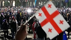 Διαδηλωτής κρατά σημαία της Γεωργίας κατά τη διάρκεια συγκέντρωσης διαμαρτυρίας για την απόφαση της κυβέρνησης να αναστείλει τις διαπραγματεύσεις με την ΕΕ στην Τιφλίδα, 5 Δεκεμβρίου 2024.
