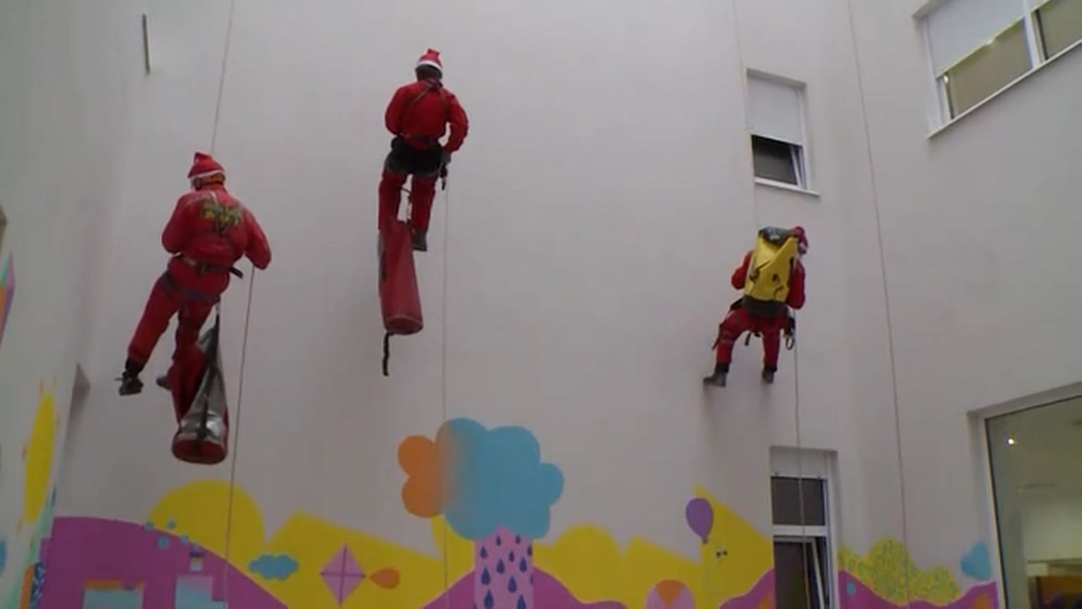 Miembros del Servicio de Rescate en Montaña, vestidos de Papá Noel, descienden por la clínica universitaria de Mostar, Bosnia-Herzegovina, 06.12.2024