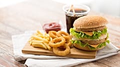 Bu stok görselde bir burger, patates kızartması, kola, ketçap ve mayonez bulunuyor