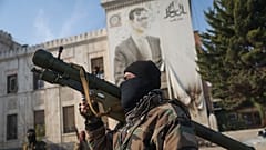 Μαχητής της συριακής αντιπολίτευσης κρατά εκτοξευτή ρουκετών μπροστά από το γραφείο της επαρχιακής κυβέρνησης στη Χάμα, 6 Δεκεμβρίου 2024.