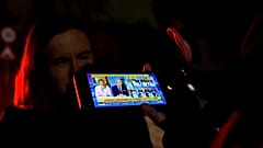 Um jornalista ouve no seu telemóvel uma entrevista em direto de Calin Georgescu para um canal de televisão local, depois de a CCR ter anulado a primeira volta da votação presidencial