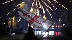 Διαδηλωτής ανεμίζει τη γεωργιανή σημαία κατά τη διάρκεια διαμαρτυρίας στην Τιφλίδα, 7 Δεκεμβρίου 2024