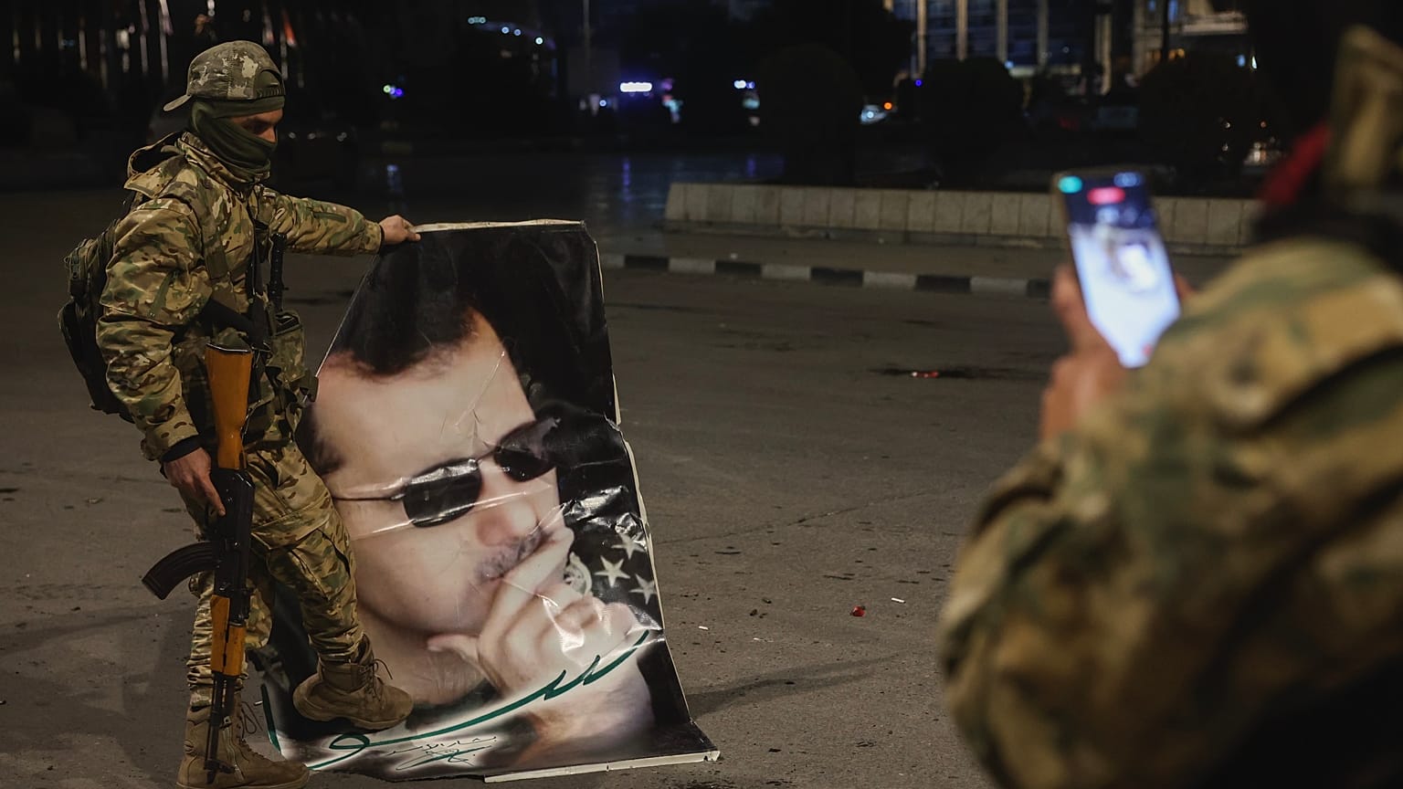 Suriyeli muhalif bir militan, 30 Kasım 2024 Cumartesi sabahı Halep'te Suriye Devlet Başkanı Beşşar Esad'ın portresine basan bir yoldaşının fotoğrafını çekiyor.