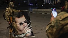Suriyeli muhalif bir militan, 30 Kasım 2024 Cumartesi sabahı Halep'te Suriye Devlet Başkanı Beşşar Esad'ın portresine basan bir yoldaşının fotoğrafını çekiyor.