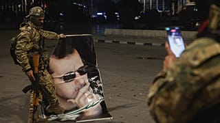 Suriyeli muhalif bir militan, 30 Kasım 2024 Cumartesi sabahı Halep'te Suriye Devlet Başkanı Beşşar Esad'ın portresine basan bir yoldaşının fotoğrafını çekiyor.