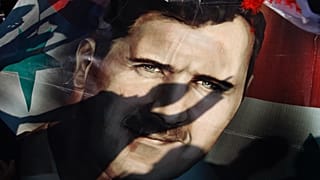 Suriye'nin başkenti Şam'da 16 Aralık 2011 Cuma günü düzenlenen destek mitinginde Devlet Başkanı Beşşar Esad'ı gösteren dev poster üzerinde Suriyelilerin gölgeleri görülüyor.