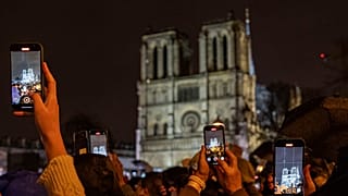 Spectators take snapshots outside France's iconic Notre Dame Cathedral Saturday, Dec. 7, 2024 in Paris during it's formal reopening for the first time since a devastating fire