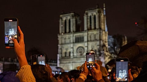 Spectators take snapshots outside France's iconic Notre Dame Cathedral Saturday, Dec. 7, 2024 in Paris during it's formal reopening for the first time since a devastating fire