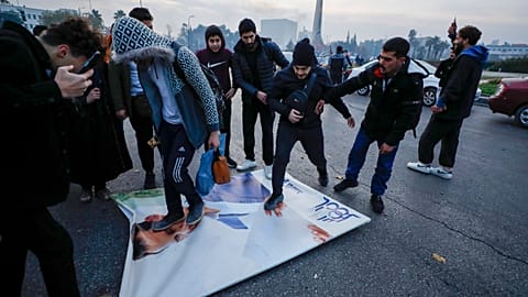 Сирийцы празднуют прибытие бойцов оппозиции, растаптывая фотографию президента Сирии Башара Асада в Дамаске, Сирия, воскресенье, 8 декабря 2024 года.