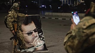 Suriyeli muhalif bir militan, 30 Kasım 2024 Cumartesi sabahı Halep'te Suriye Devlet Başkanı Beşşar Esad'ın portresine basan birinin fotoğrafını çekiyor.
