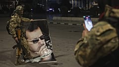 Ένας μαχητής της συριακής αντιπολίτευσης φωτογραφίζει έναν σύντροφό του που πατάει πάνω στο πορτρέτο του Σύρου προέδρου Μπασάρ Άσαντ στο Χαλέπι, 30 Νοεμβρίου 2024.