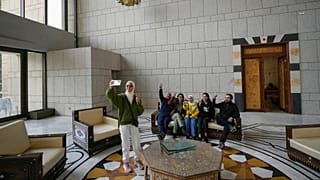 Um grupo de pessoas tira uma fotografia de família numa sala do palácio presidencial do presidente sírio Bashar al-Assad em Damasco, Síria, 8.12.2024