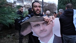 Um homem rasga uma fotografia do Presidente sírio Bashar Assad em frente à embaixada da Síria em Belgrado, 8 de dezembro de 2024