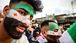 أشخاص رسموا علم المعارضة السورية على وجوههم أثناء حضورهم مسيرة في ألمانيا  8 كانون الأول ديسمبر 2024 