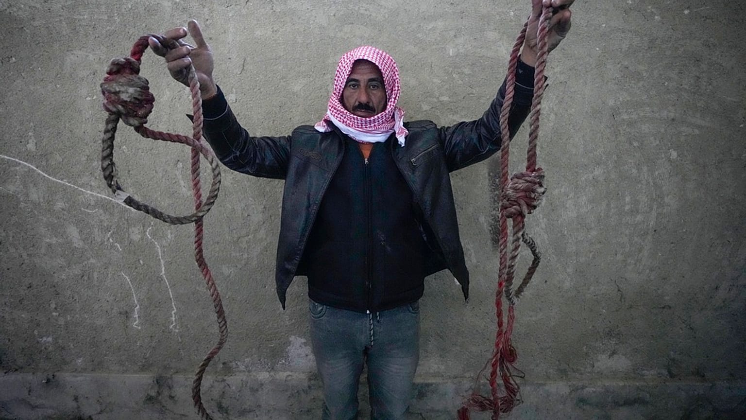 رجل يحمل حبليْن على شكل مشانق وُجدت بسجن صيدنايا، مع توافد حشود بحثًا عن أقاربهم بعد سقوط الأسد.
