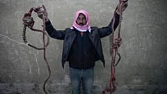 رجل يحمل حبليْن على شكل مشانق وُجدت بسجن صيدنايا، مع توافد حشود بحثًا عن أقاربهم بعد سقوط الأسد.