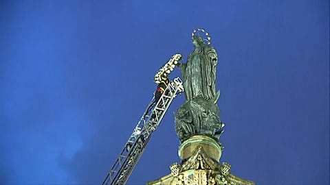 Pompier déposant une couronne de fleurs sur le bras de la statue de la Vierge Marie, à Rome en Italie, le 08.12.2024
