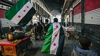 Des partisans de l'opposition portent des drapeaux de l'opposition sur le marché Al-Hamidiyeh dans la vieille ville fortifiée de Damas, Syrie, mardi 10 décembre 2024.