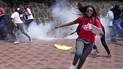 Manifestantes huyen de una nube de gas lacrimógeno disparado por la policía antidisturbios durante la marcha contra el feminicidio, Nairobi, Kenia, 10.12.2024.