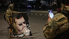 Un combatiente de la oposición siria hace una foto a un compañero que pisa un retrato del derrocado presidente sirio Bashar Assad en Alepo.