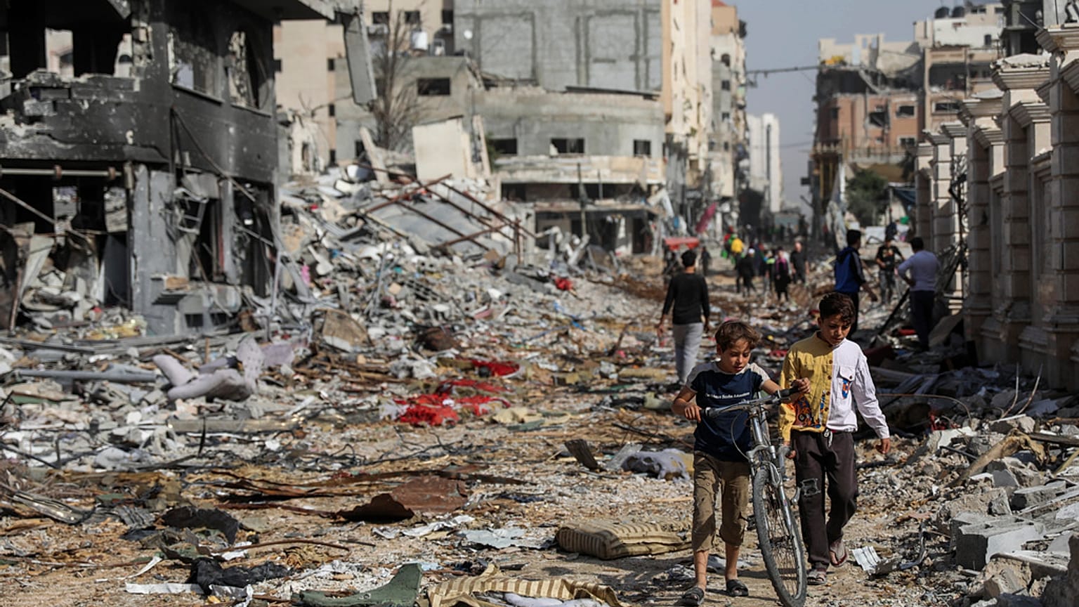 فلسطينيون يسيرون وسط الدمار في مدينة غزة يوم الجمعة، 24 نوفمبر 2023