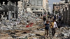 فلسطينيون يسيرون وسط الدمار في مدينة غزة يوم الجمعة، 24 نوفمبر 2023