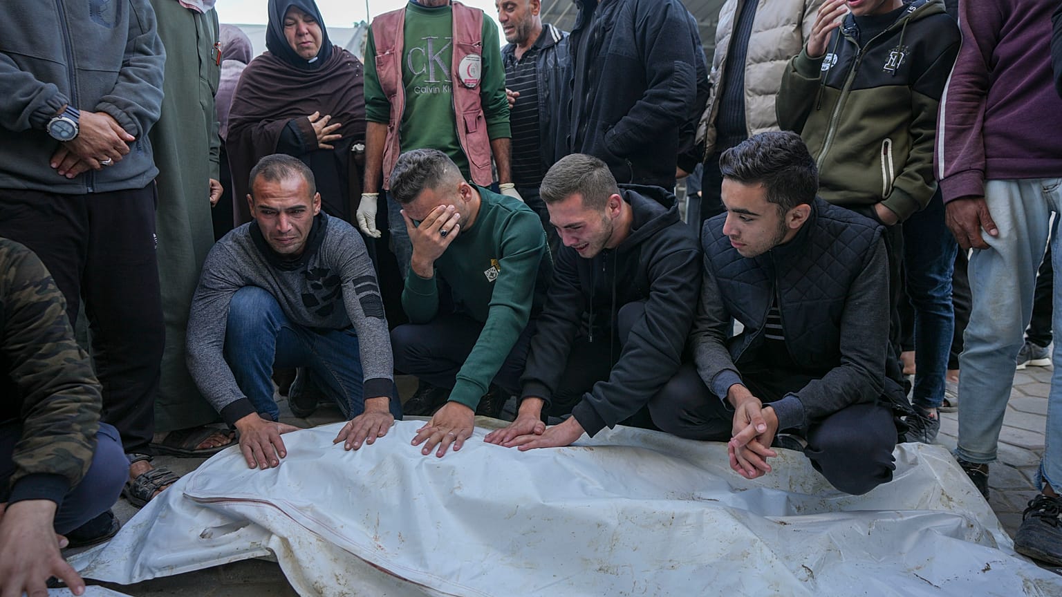 Gazze Şeridi'ndeki El Aksa Şehitler Hastanesi'nin avlusunda bir grup insan yakınlarının cenazesinin başında bekliyor, 9 Aralık 2024
