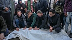 Gazze Şeridi'ndeki El Aksa Şehitler Hastanesi'nin avlusunda bir grup insan yakınlarının cenazesinin başında bekliyor, 9 Aralık 2024