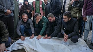 Gazze Şeridi'ndeki El Aksa Şehitler Hastanesi'nin avlusunda bir grup insan yakınlarının cenazesinin başında bekliyor, 9 Aralık 2024
