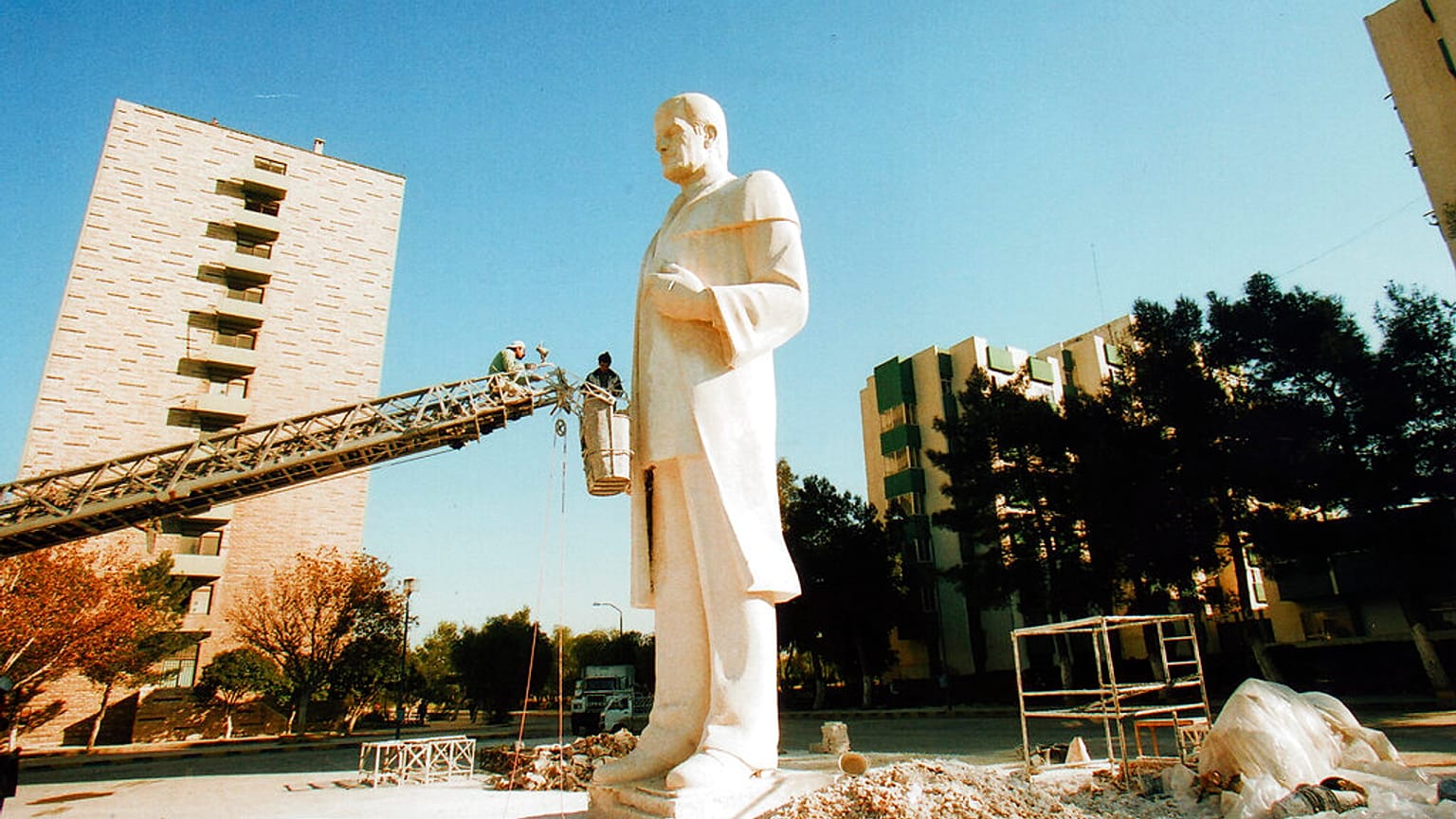 عمال يقومون بتثبيت تمثال للرئيس السوري السابق حافظ الأسد في مدينة سكن طلاب جامعة دمشق، في سوريا.