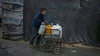 فلسطيني يدفع كرسيًا متحركًا في مخيم للنازحين في دير البلح، قطاع غزة، الخميس 12 ديسمبر 2024.