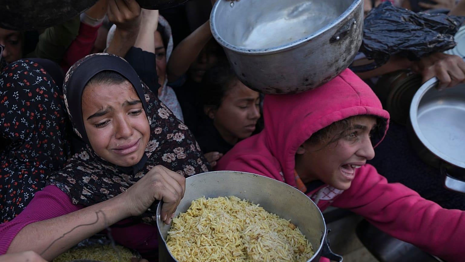 Bambine cercano cibo in un centro di distribuzione di aiuti a Khan Younis, nella Striscia di Gaza