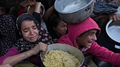 Niñas palestinas buscan alimentos en un centro de distribución en Khan Younis, Gaza, en plena crisis humanitaria