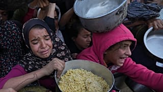 Niñas palestinas buscan alimentos en un centro de distribución en Khan Younis, Gaza, en plena crisis humanitaria
