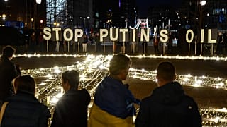 Люди стоят вокруг гигантского знака мира, установленного демонстрантами в преддверии саммита ЕС и НАТО в Брюсселе, вторник, 22 марта 2022 года.